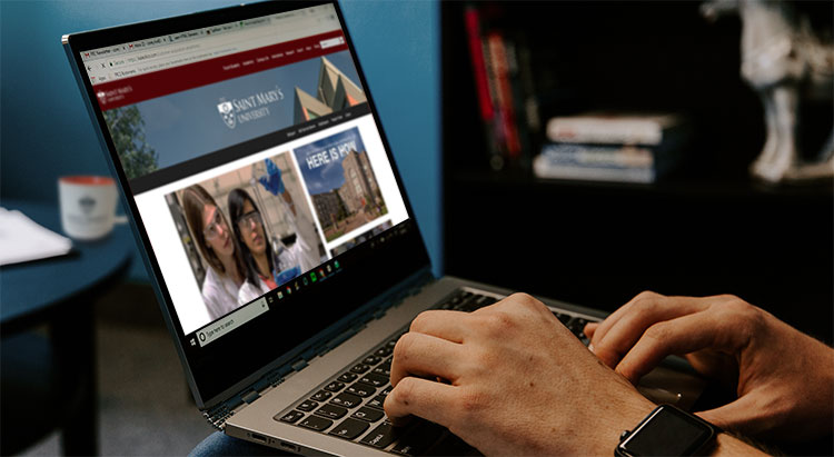 Hands on the keyboard of a notebook computer with the FIH's homepage.